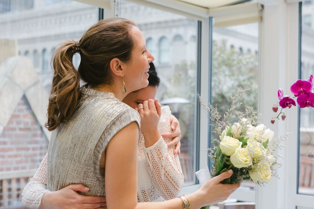a candid view of an older sister embracing his young sister while she becomes emotional at her wedding in NYC