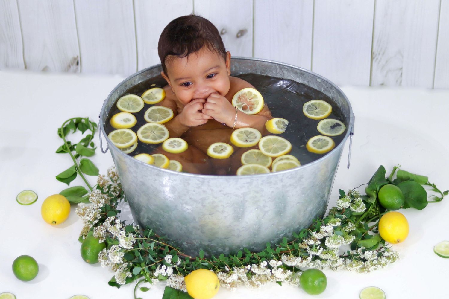 Decorative bath setup with floating lime slices and flowers against white background.