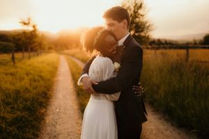 A romantic embrace at sunset on a country path with golden light filtering through.
