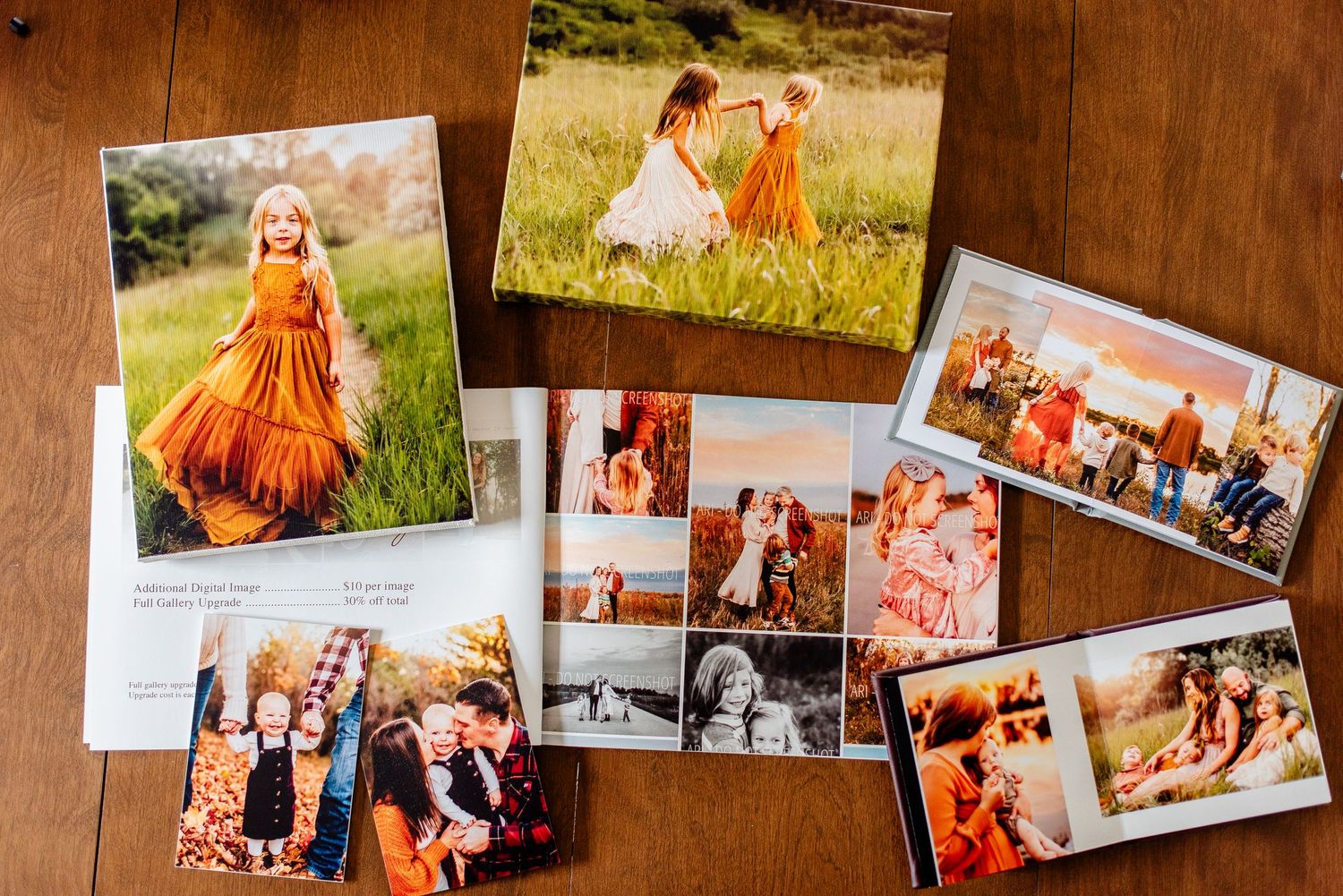 Collection of professional family photos displayed on wooden surface showing orange and white color scheme.