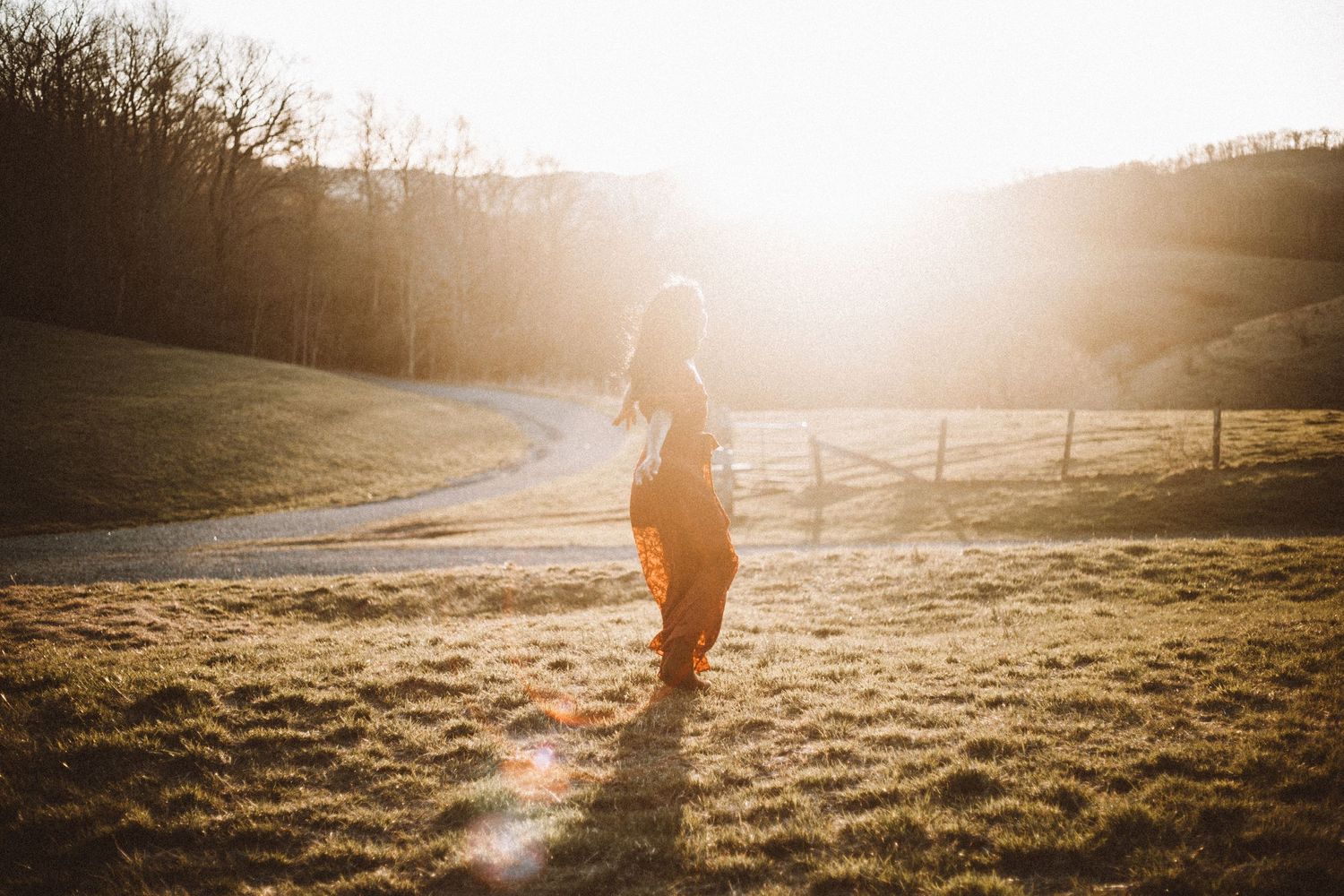 Silhouetted figure walking in golden sunlit field at sunset.