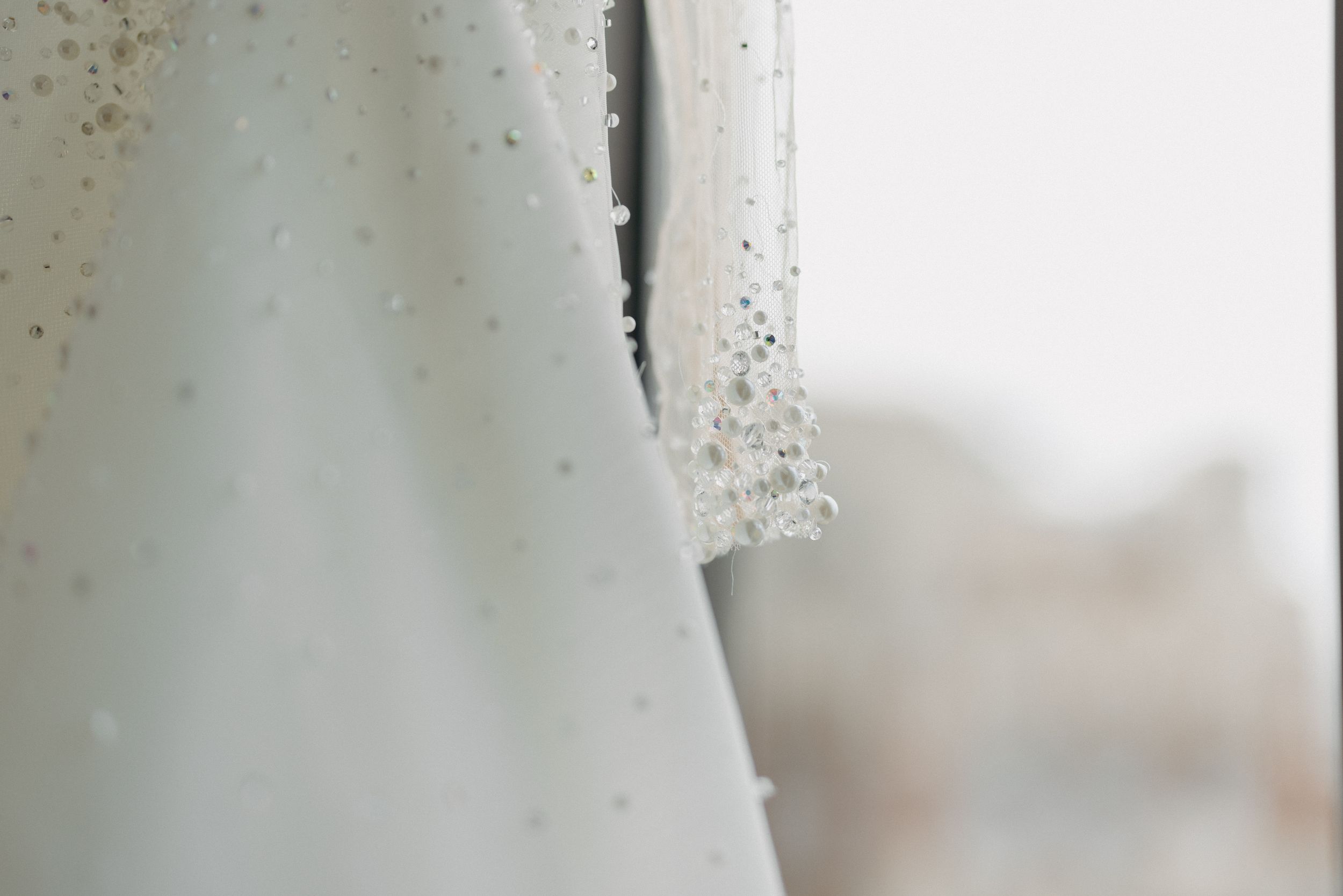 Close-up detail of sparkly embellishments on a white wedding dress.