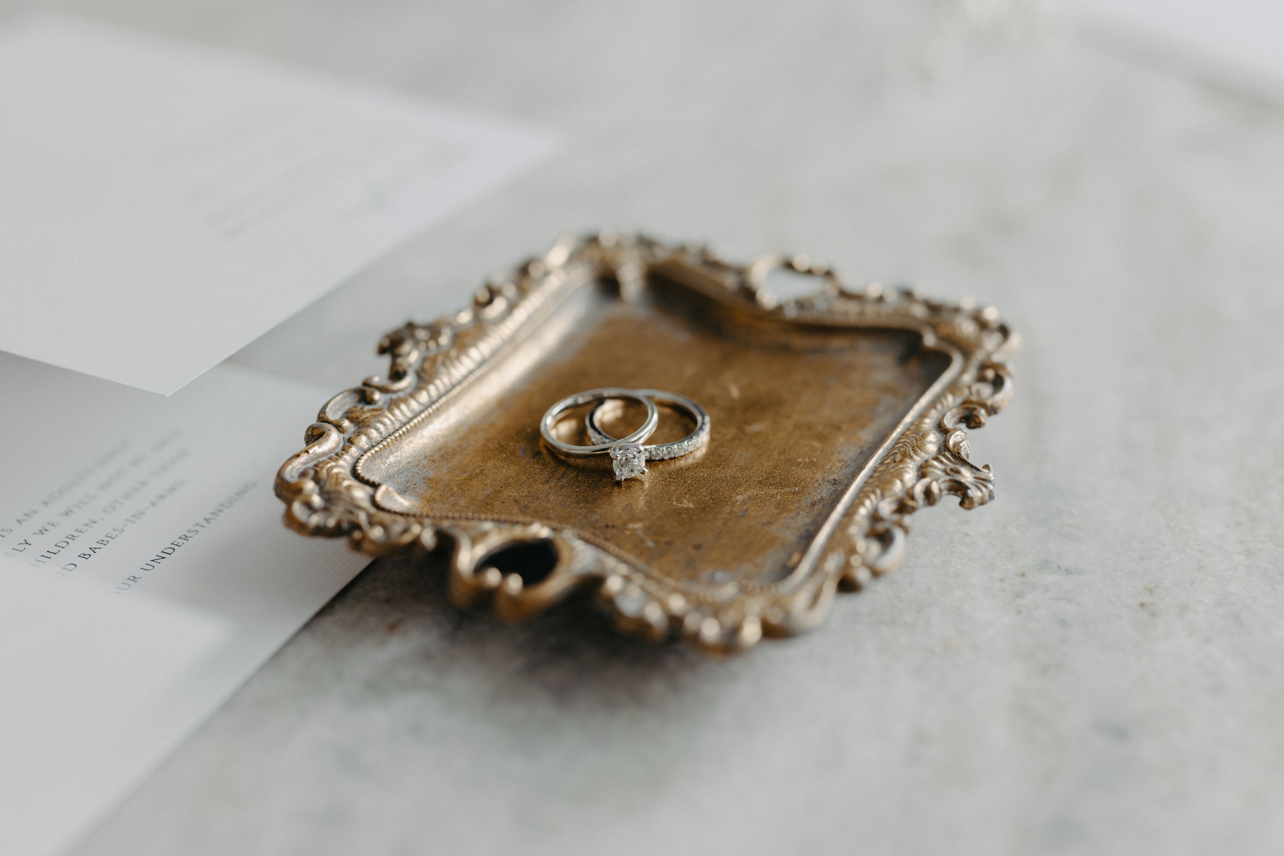Wedding rings displayed on vintage ornate gold tray with antique design.