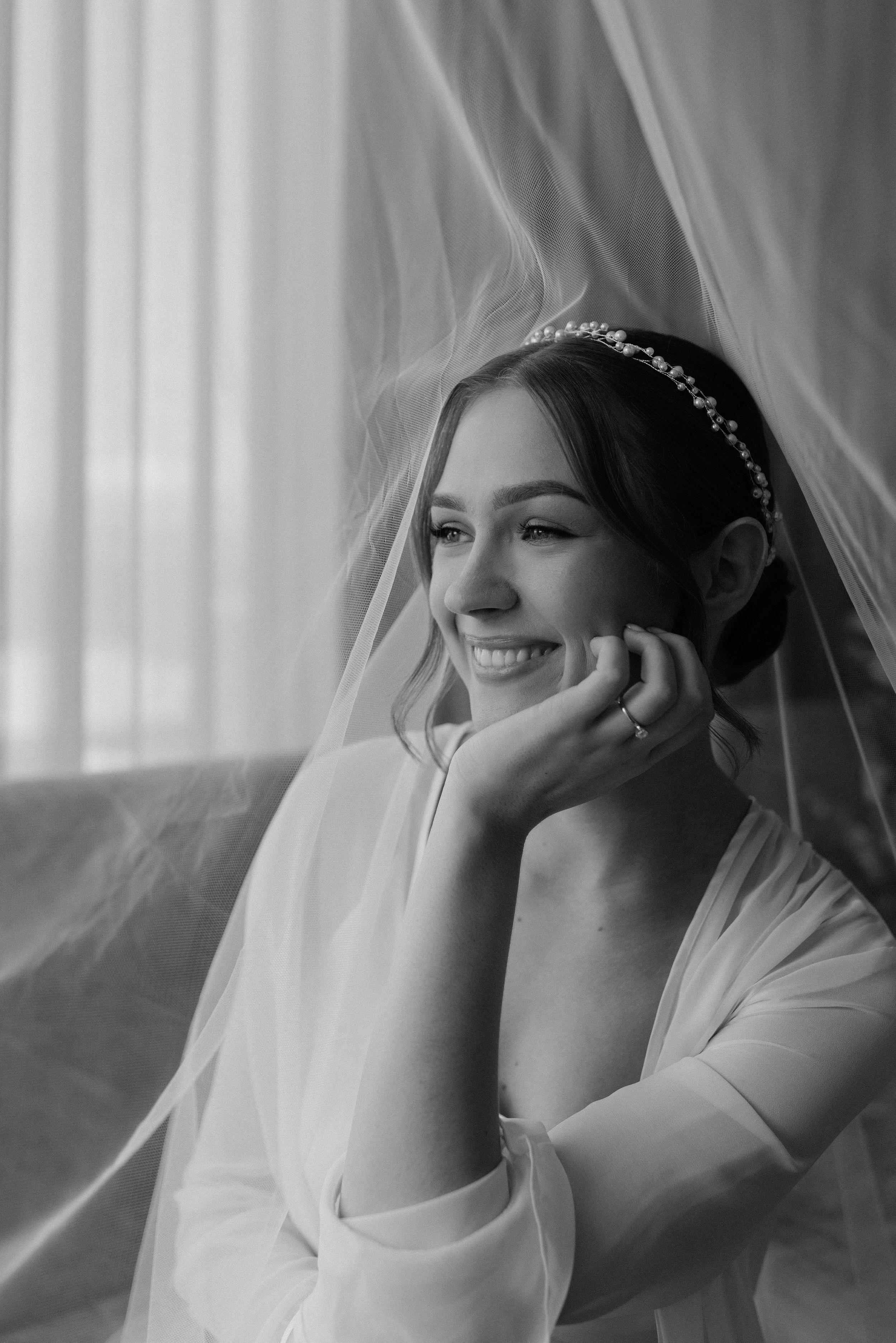 Black and white portrait of a smiling bride wearing a delicate tiara and veil.