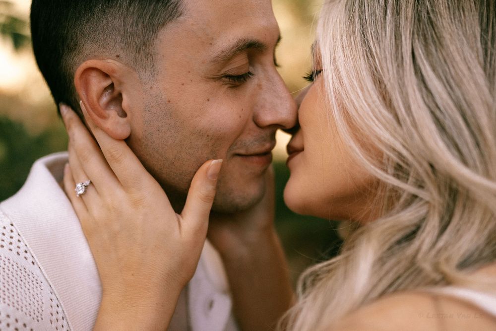 Close up of couple in romantic outdoor engagement photos wearing white and sharing intimate moments during golden hour.