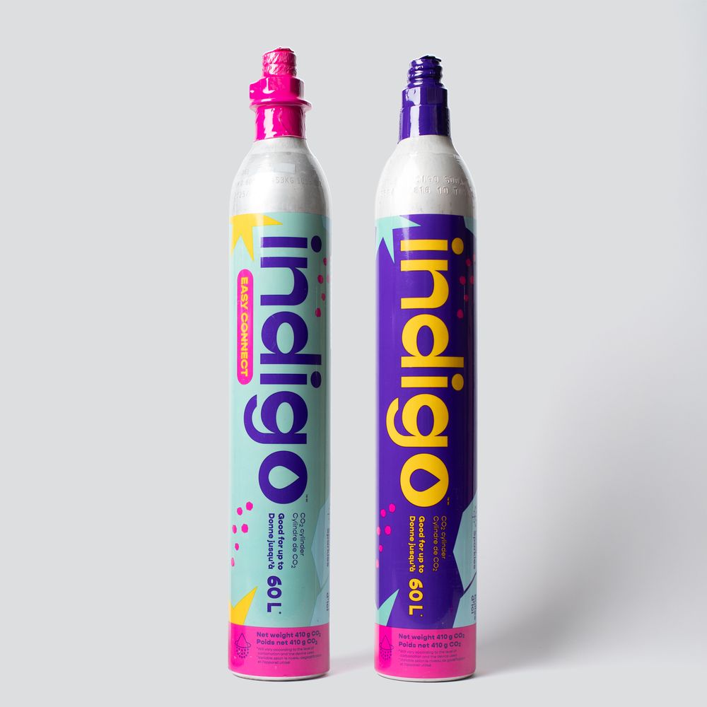 Two Indigo 60L CO2 carbonation cylinders side by side, one pink and one purple, on a gray background.
