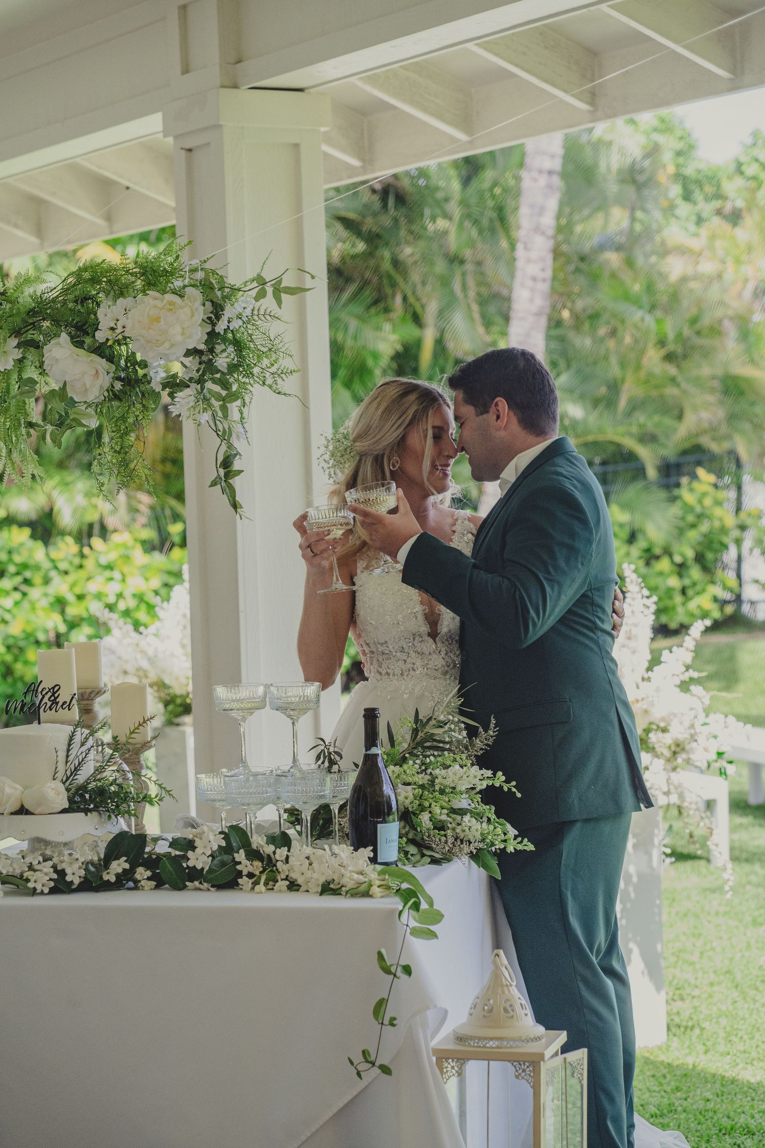 An intimate wedding toast moment in an elegant white gazebo decorated with floral arrangements.