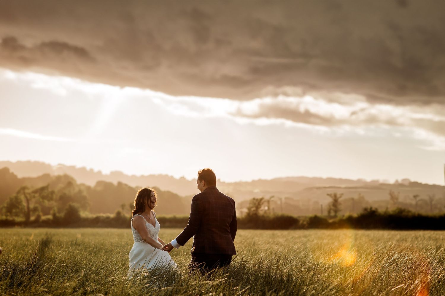 Silhouetted figures sit together on a hill during a dramatic sunset.