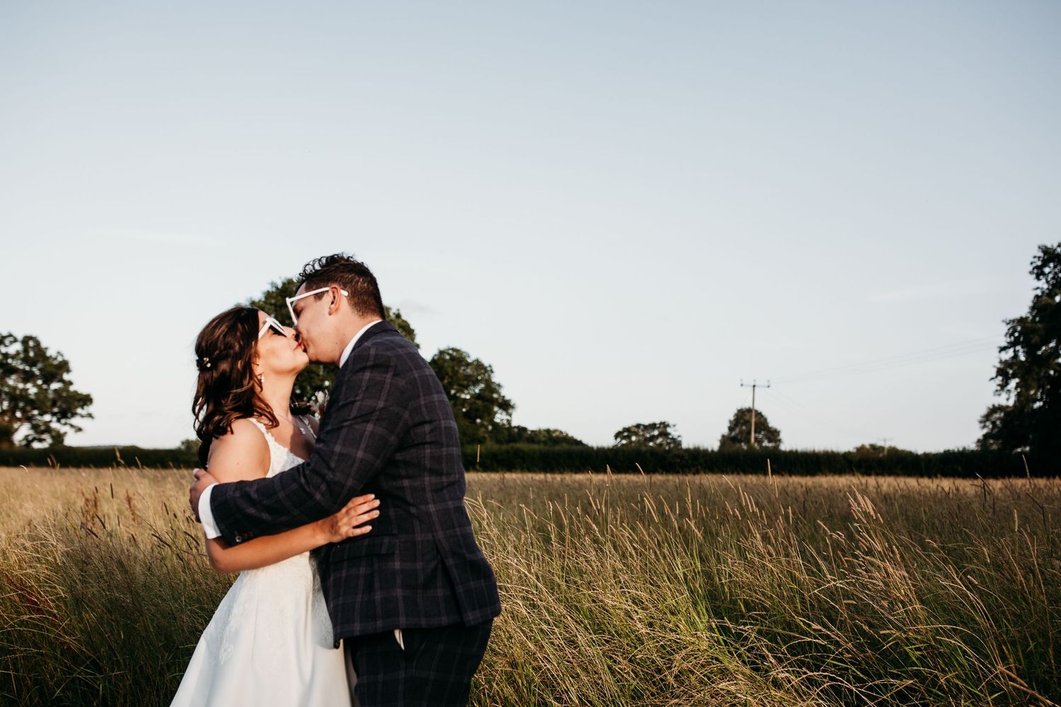 Couple embraces in a golden wheat field during their wedding photoshoot.