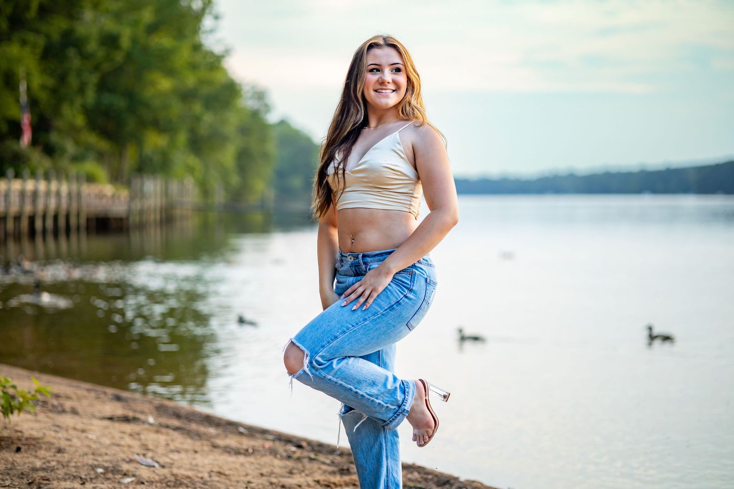 Casual fashion shoot by lake with ripped jeans and crop top.