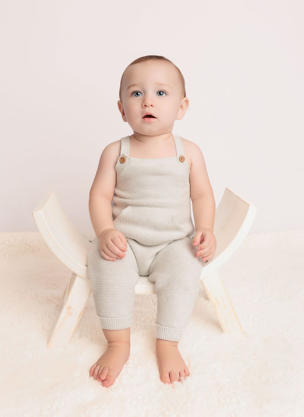 Simple studio portrait with beige romper and minimalist setting.