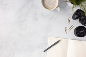 Flat lay of camera gear, coffee, journal, pen and plant on marble counter top Seattle, WA branding stock images