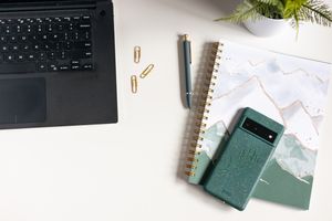 flat lay stock image branded photos of laptop, notebook and green phone case with pen