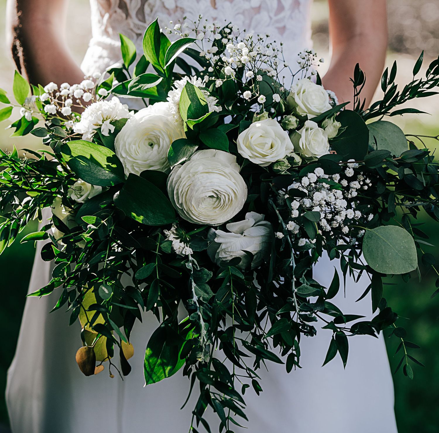 Lush white and green floral arrangements with roses and eucalyptus leaves.