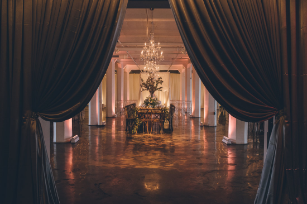 Grand hallway with dramatic black curtains, crystal chandelier and polished floors.