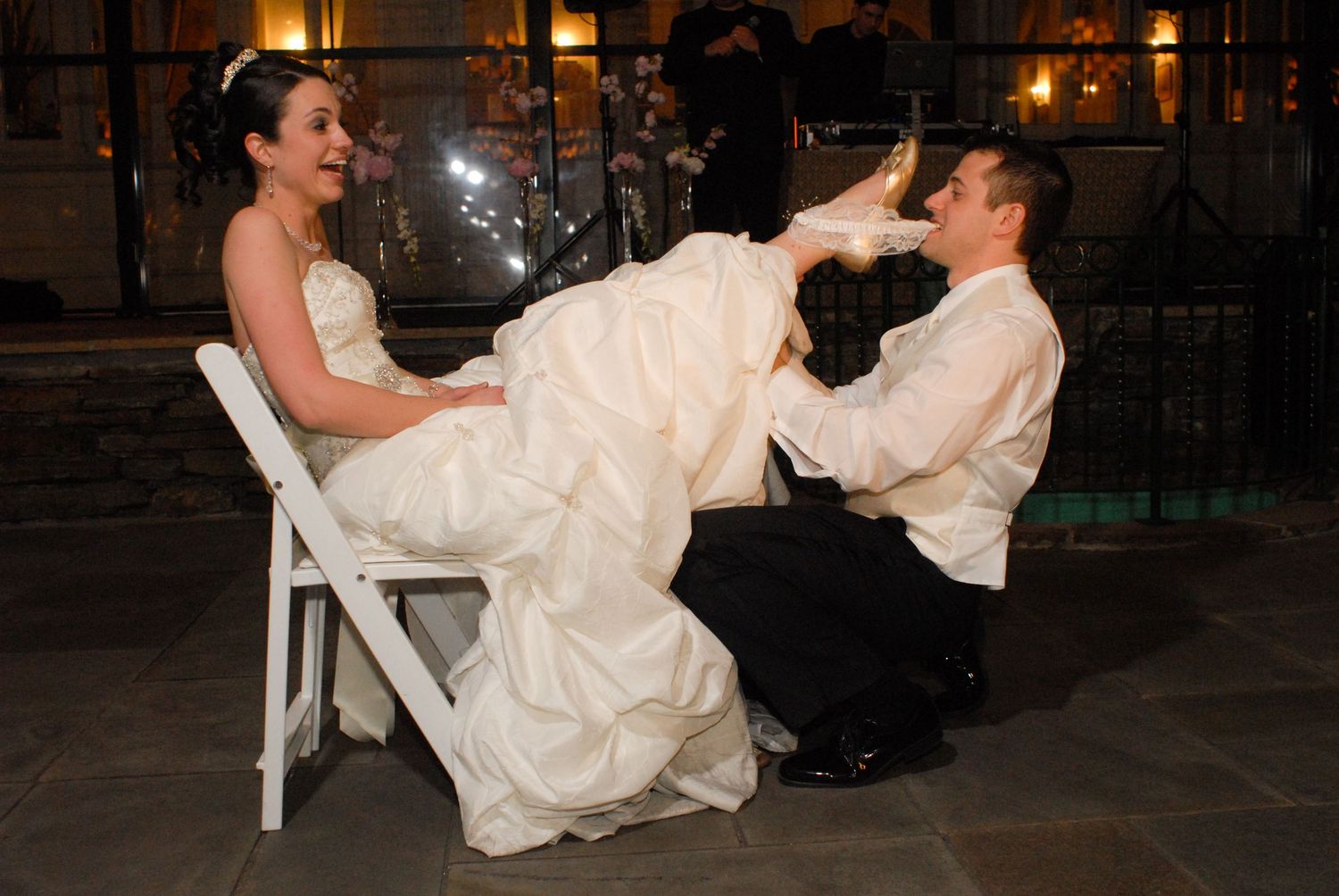 Bride and groom perform playful garter removal tradition at reception.