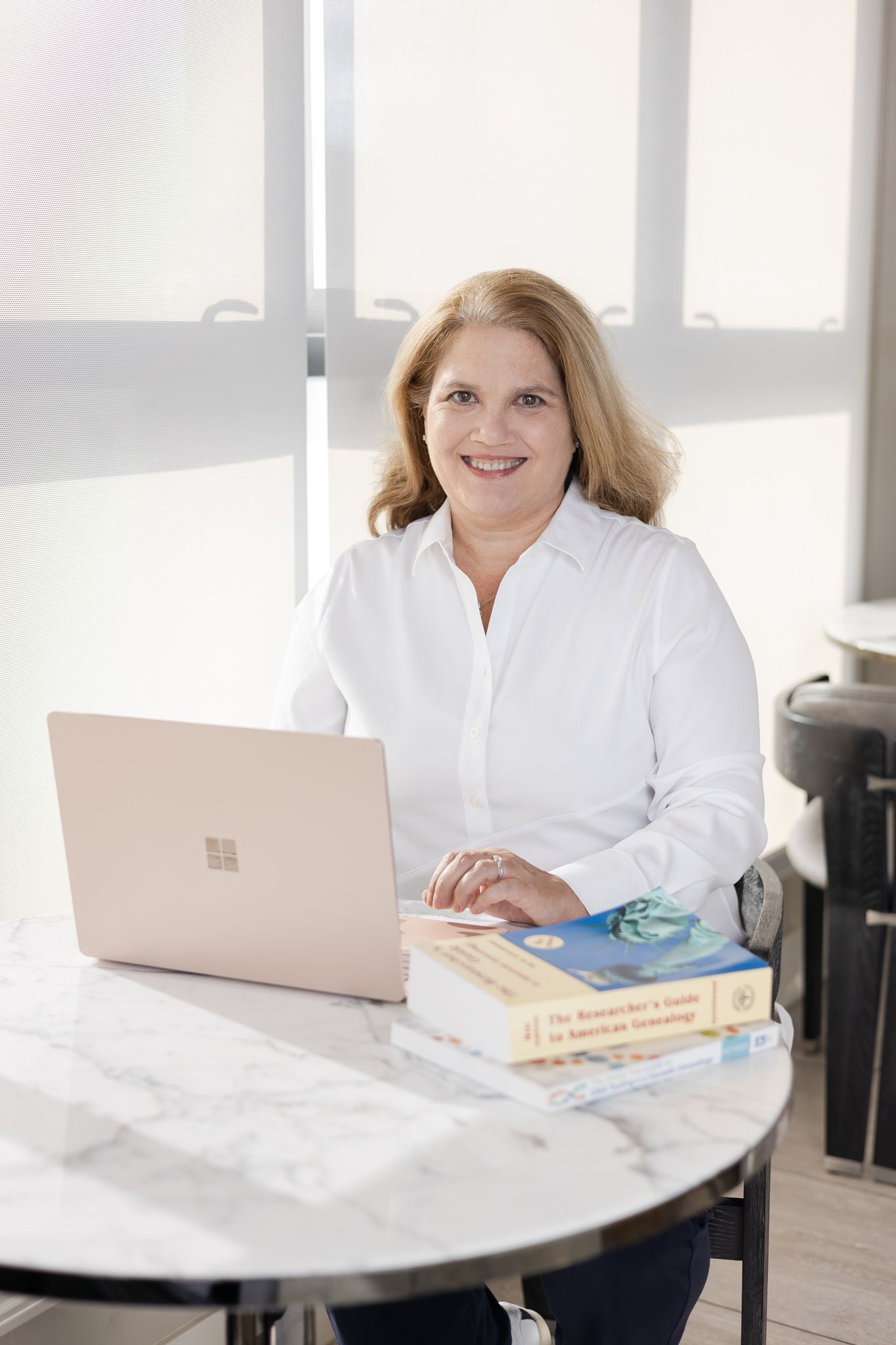 woman sitting on her computer at table with research genealogy books for headshot in Woodinville, WA