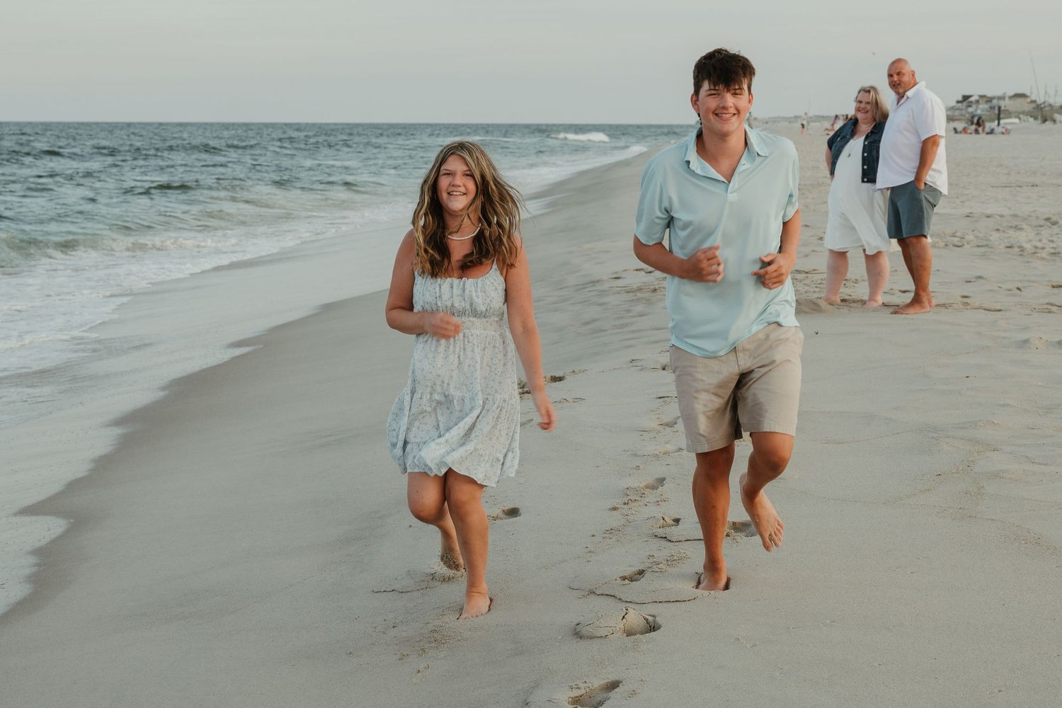 Happy couple walking barefoot along the shoreline on a peaceful beach.