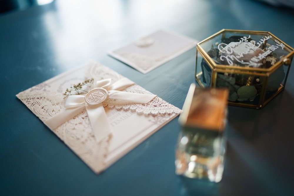 Wedding stationery with ribbon details and decorative boxes on dark surface.