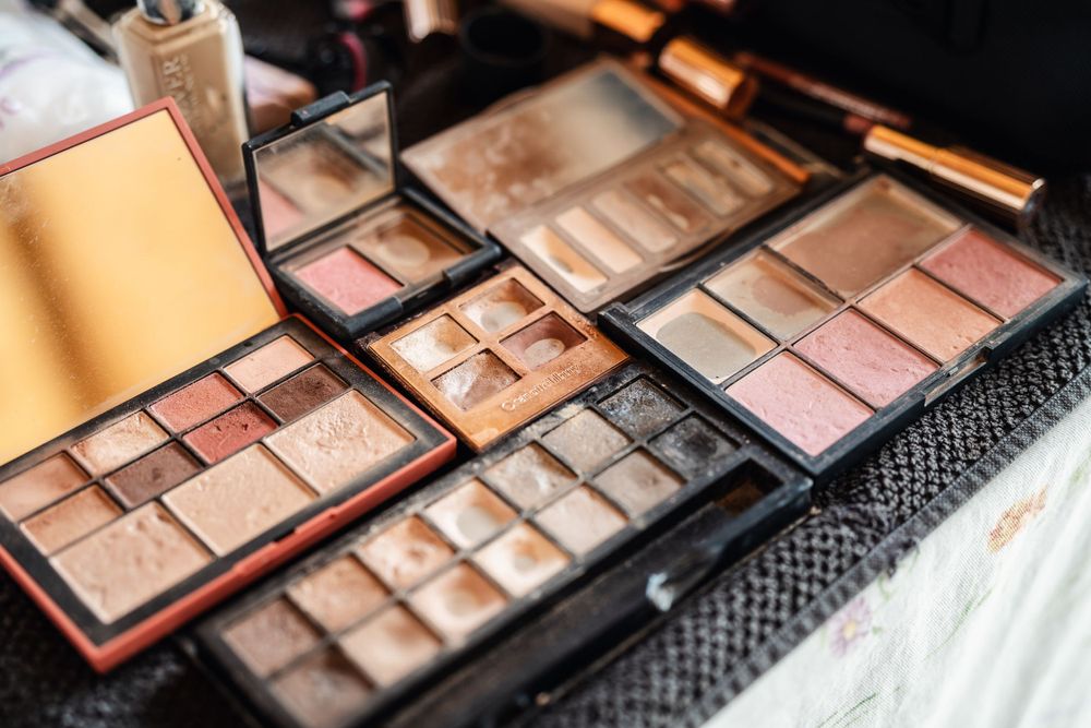 Closeup of neutral and pink toned makeup palettes with eyeshadows and highlighters.