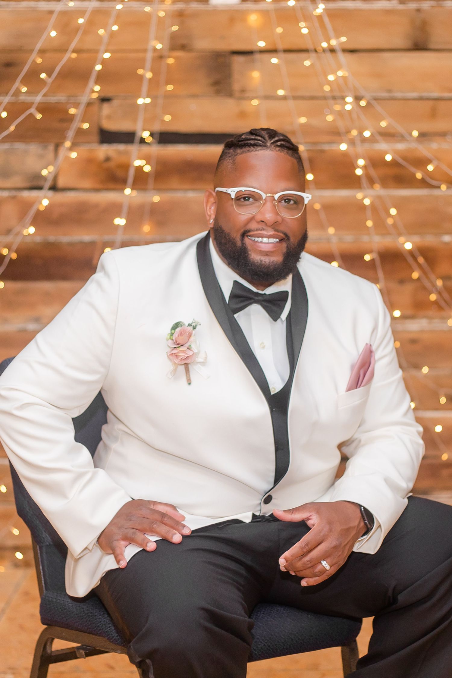 Formal wedding attire featuring white tuxedo jacket with black bow tie and trim.