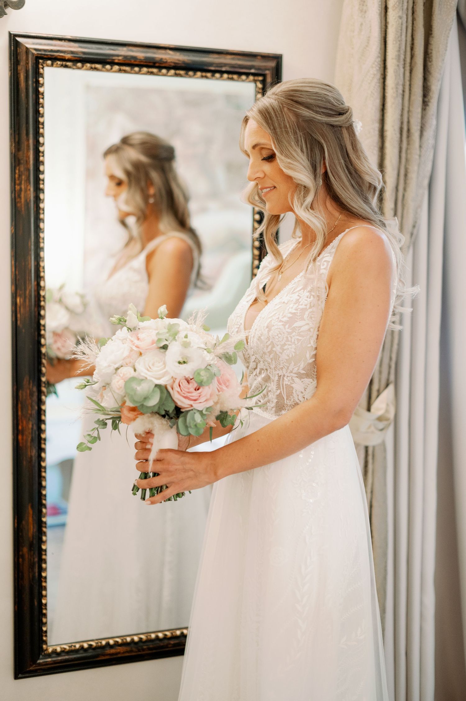 A bridal suite scene with someone holding a pink and white bouquet while wearing a lace wedding dress.