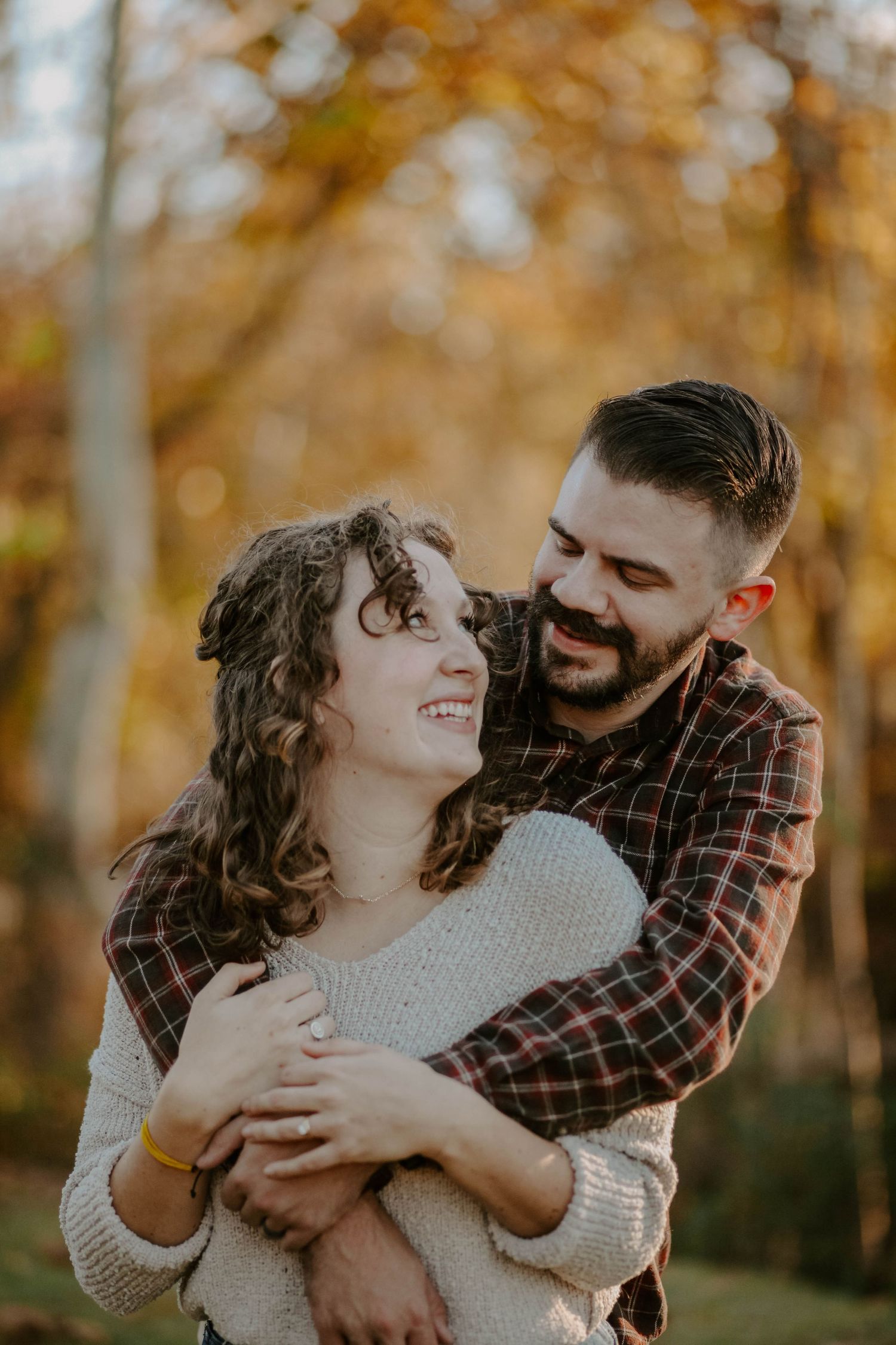 Smiling couple shares a moment in front of the camera during the fall season.