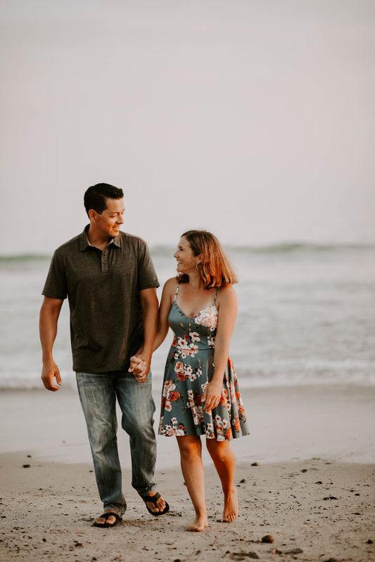 Golden hour photo of couple smiling and walking up the California beach.