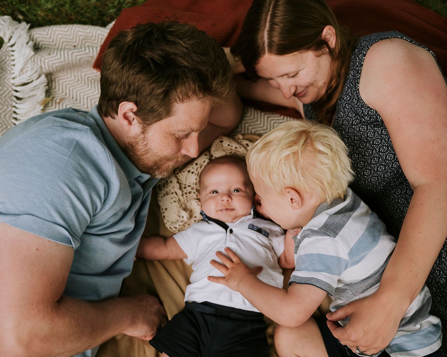 Intimate family moment captured on a cozy blanket as they cuddle close together.