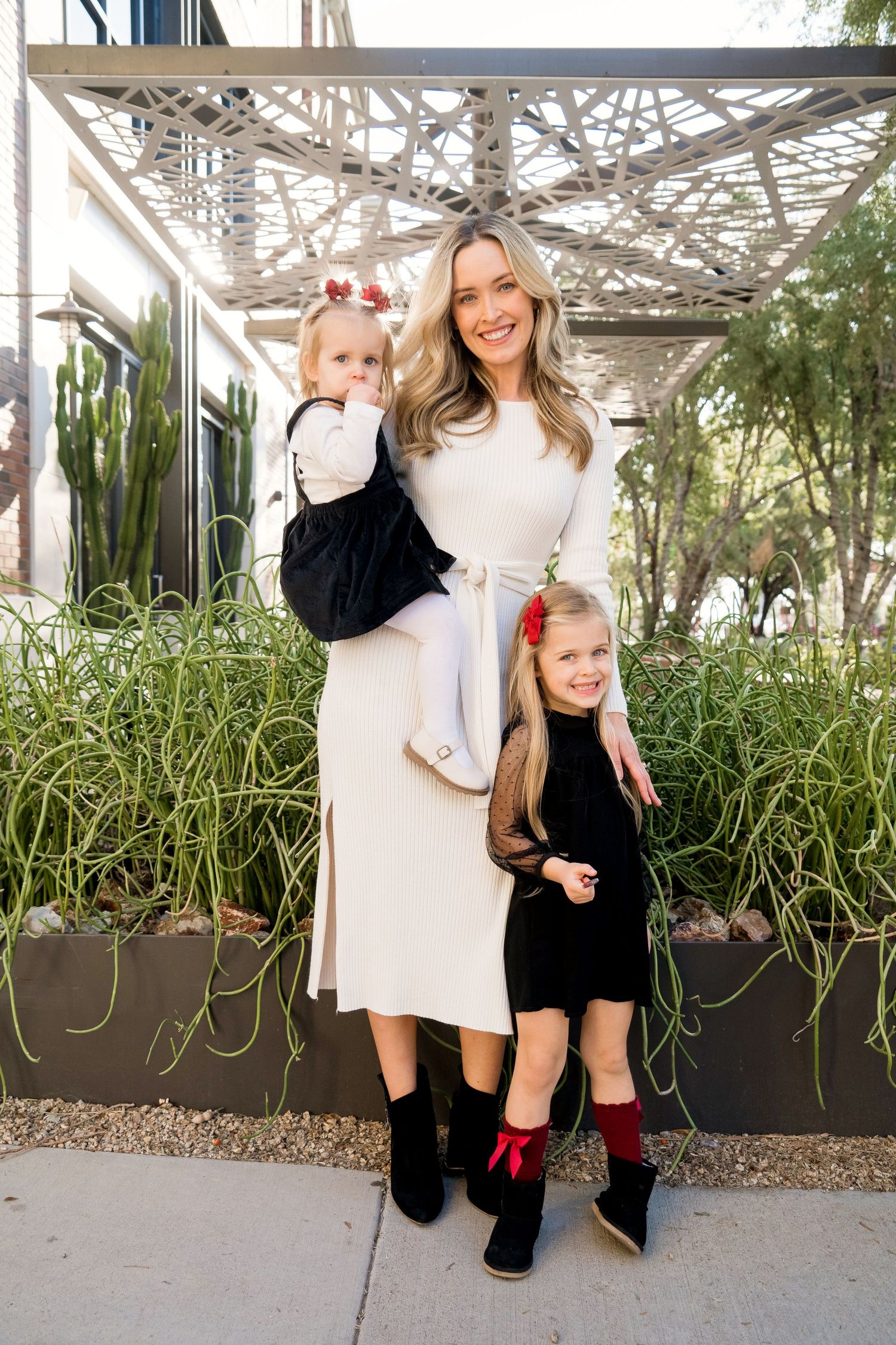 Elegant family portrait outdoors with architectural lattice and greenery backdrop.