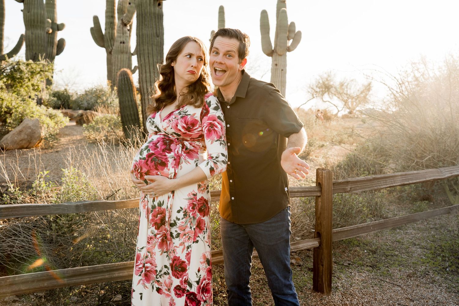 Couple embracing in desert landscape with saguaro cacti and glowing sunset.