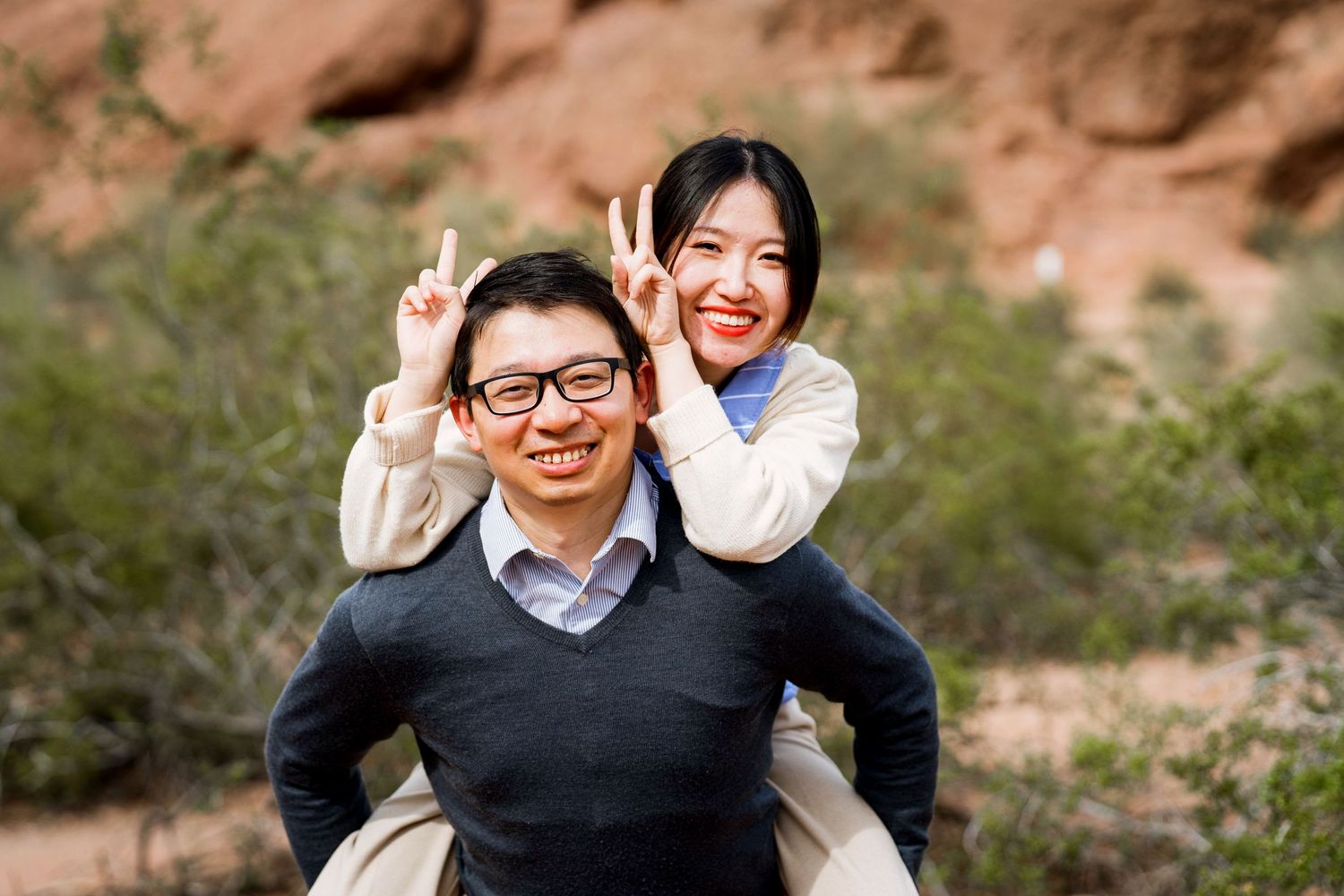 Playful couple posing together against red rock formations in a desert setting.