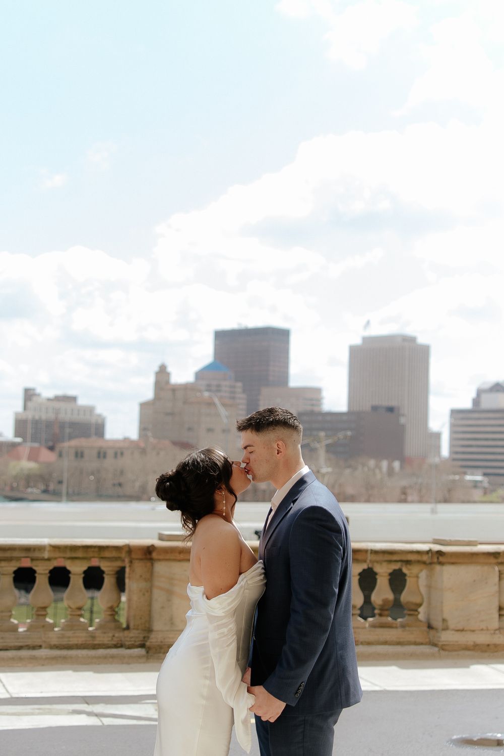 Romantic wedding couple sharing an intimate moment against a city skyline with tall buildings in the background.