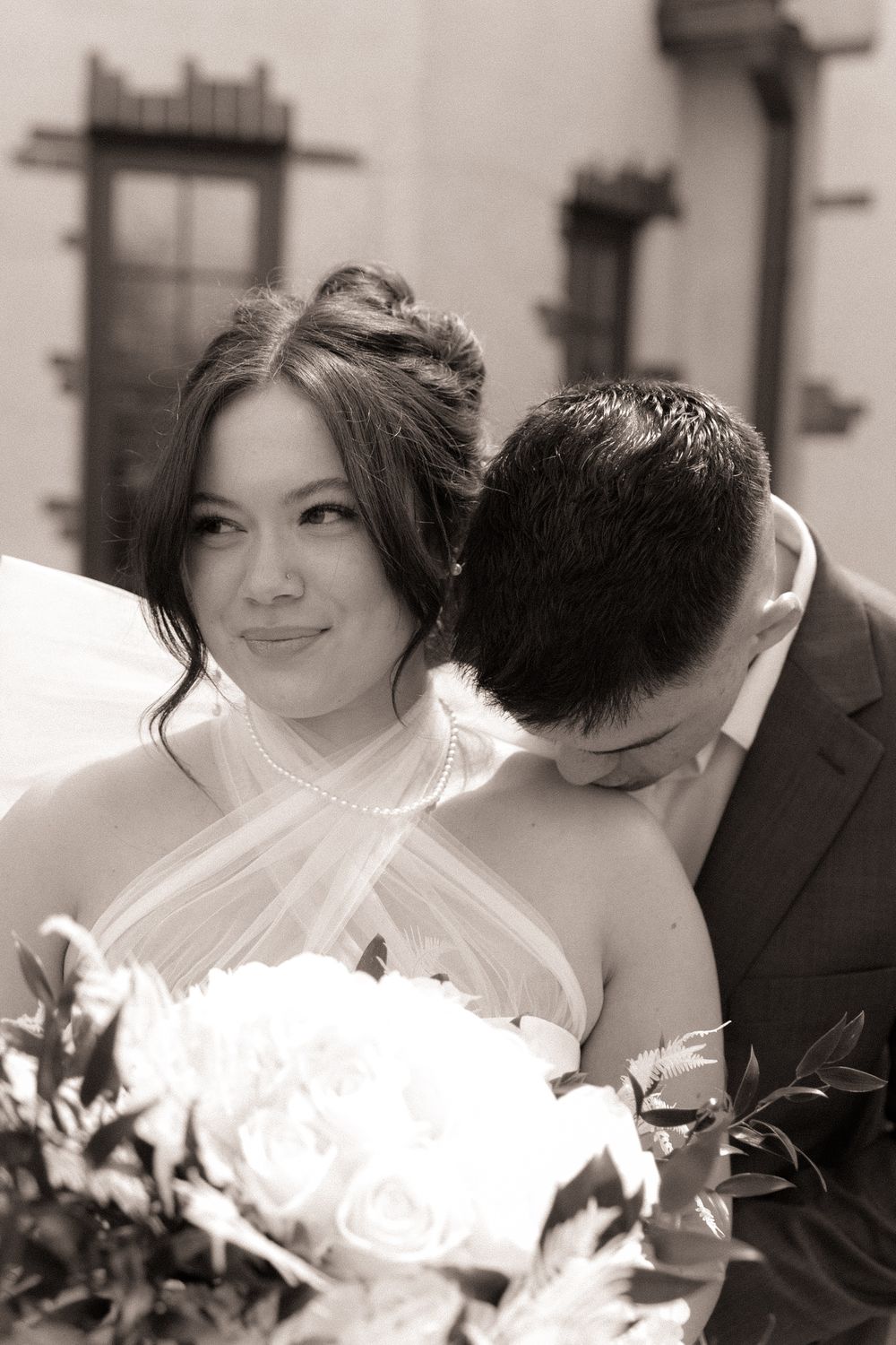 A romantic black and white wedding portrait featuring a bridal bouquet and tender moment.