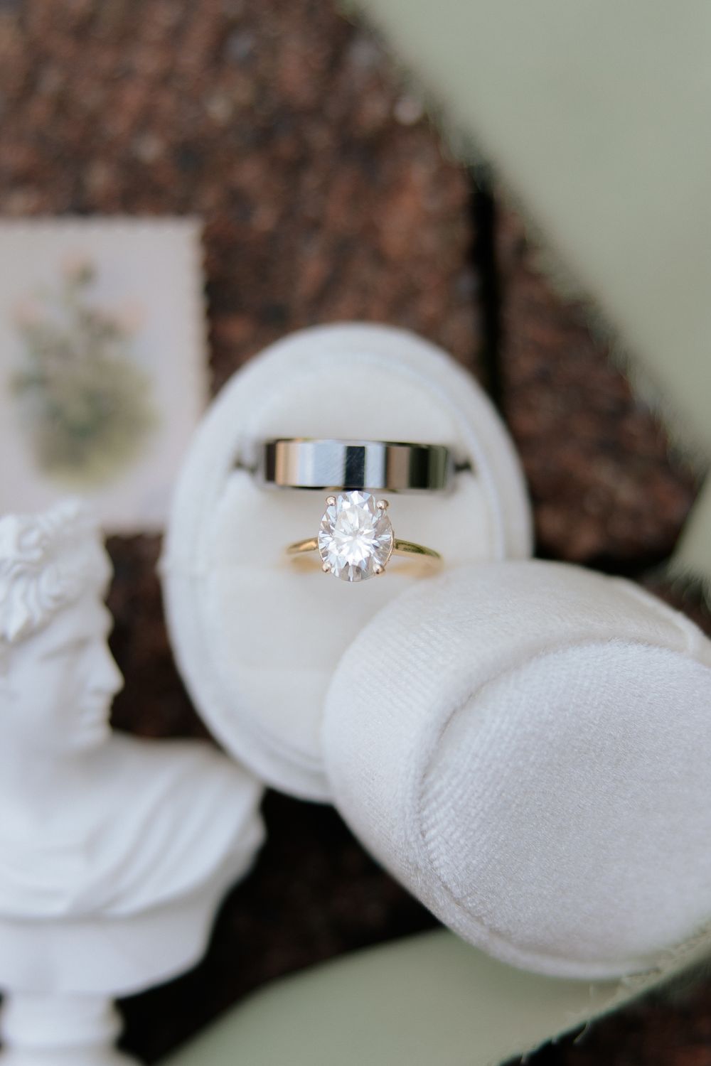 Wedding rings displayed on white fabric, featuring a diamond engagement ring and simple band.