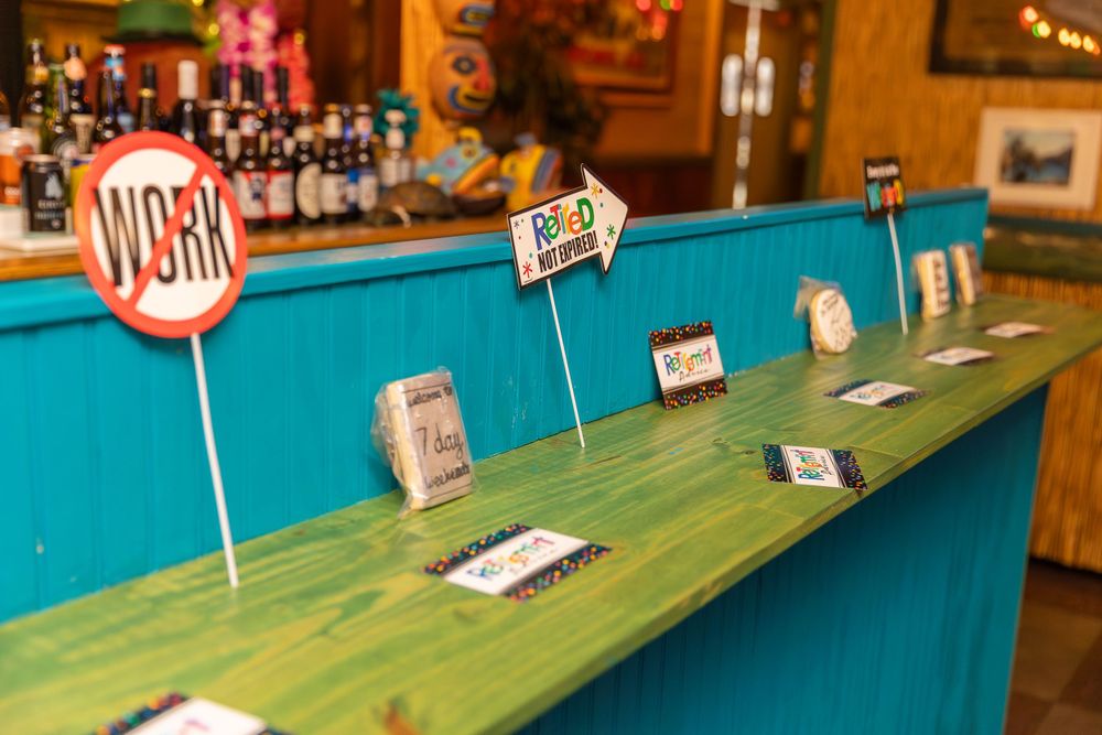 Small road sign decorations and name cards line a bright turquoise surface at a bar or restaurant setup.