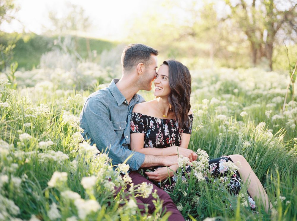 Couple sharing an intimate moment while sitting in a wildflower meadow at sunset.