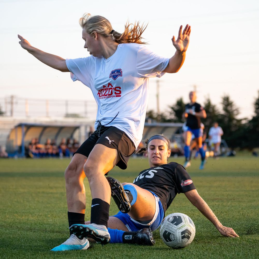 Soccer players collide in dramatic tackle during competitive match on grass field.