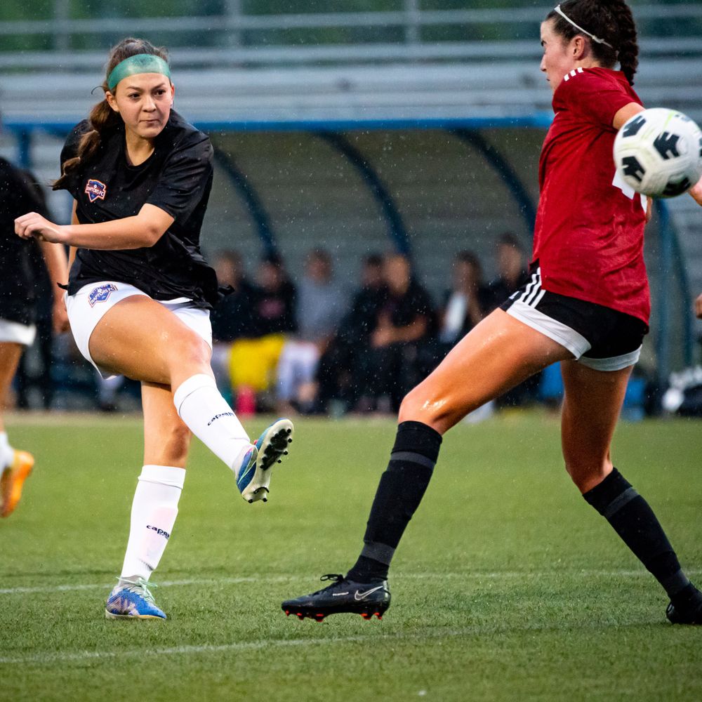 Two soccer players competing for the ball during an intense match on grass field.