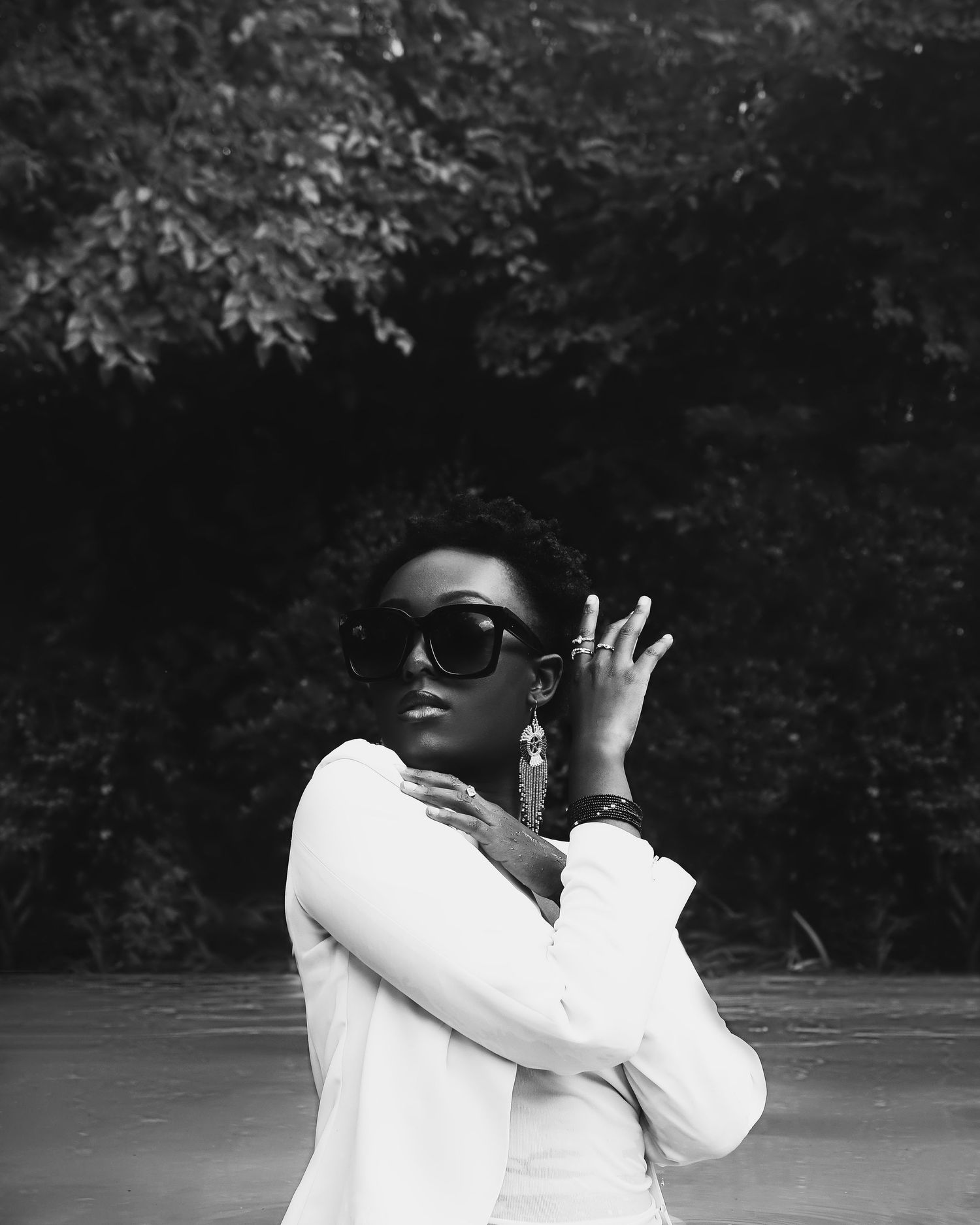 Black and white fashion portrait of someone in sunglasses and white top.
