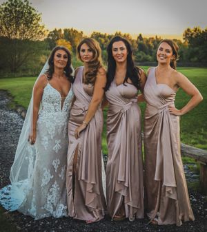 Bridal party in coordinated dusty rose and neutral dresses posing together at sunset.