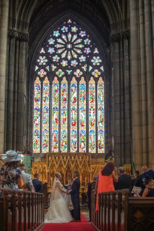 Church wedding ceremony in a cathedral with stunning stained glass windows and gothic architecture.