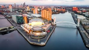 Aerial view of Belfast's waterfront showing curved bridges and modern architecture at sunset.