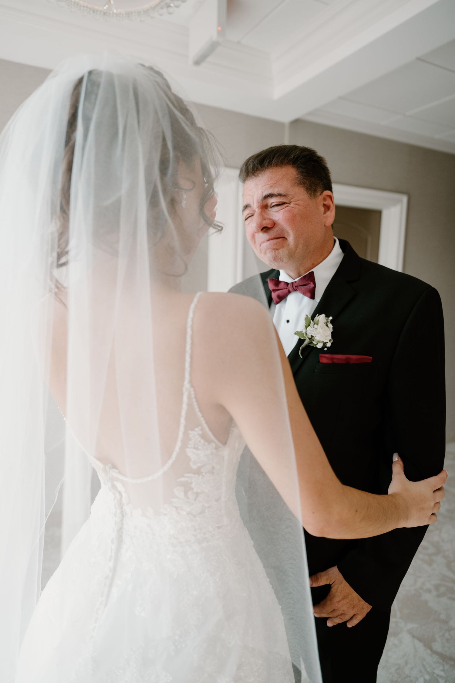 Emotional father seeing bride in wedding dress for the first time during touching first look moment.