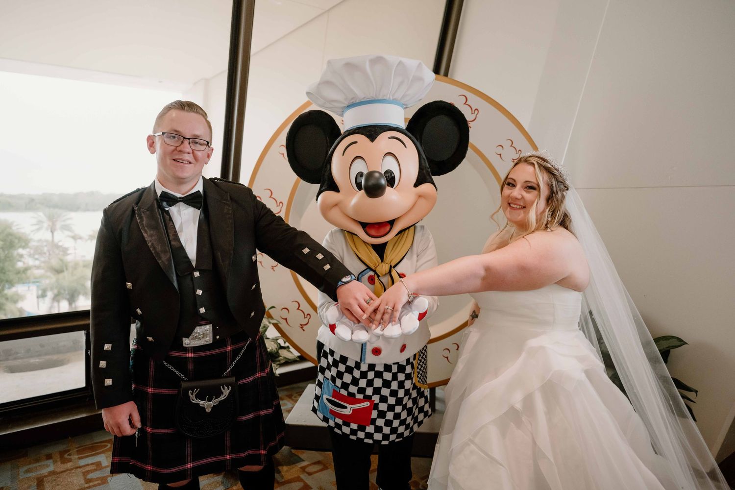 Bride and groom in Scottish kilt cutting cake with Chef Mickey Mouse at Disney World wedding.