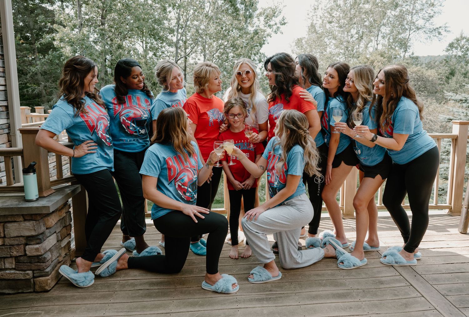 Bride celebrating with bridesmaids in colorful tie-dye shirts on a wooden deck outdoors.