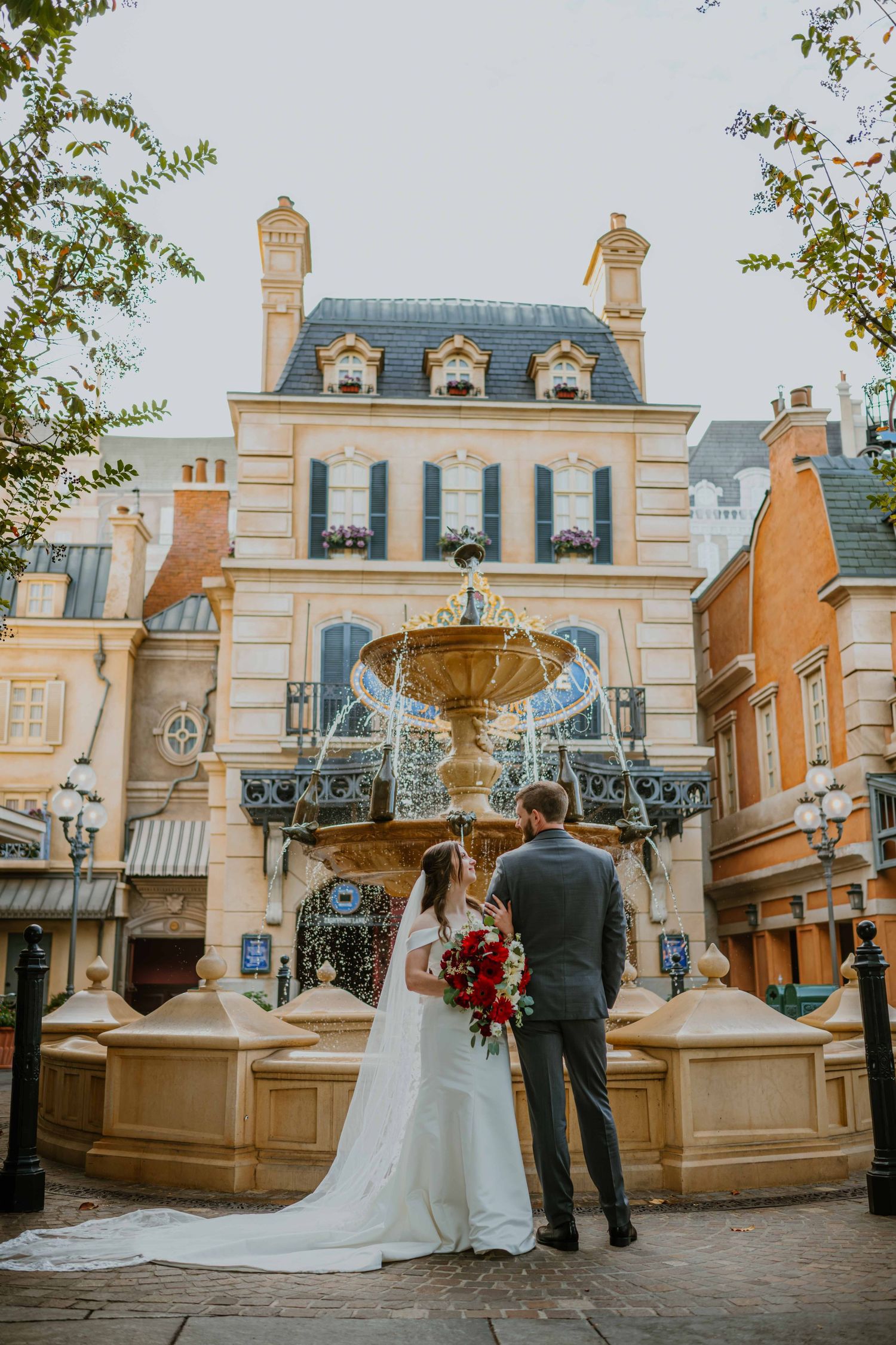 Bride and groom standing before elegant French fountain at EPCOT France pavilion wedding portrait.