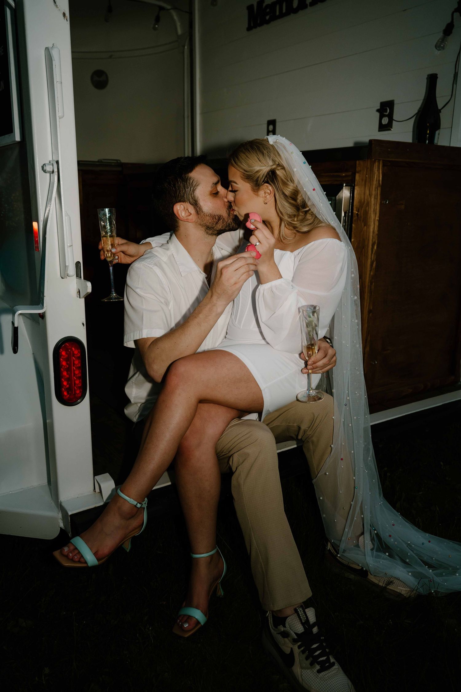 Bride and groom share a sweet moment with champagne inside a decorated wedding van.