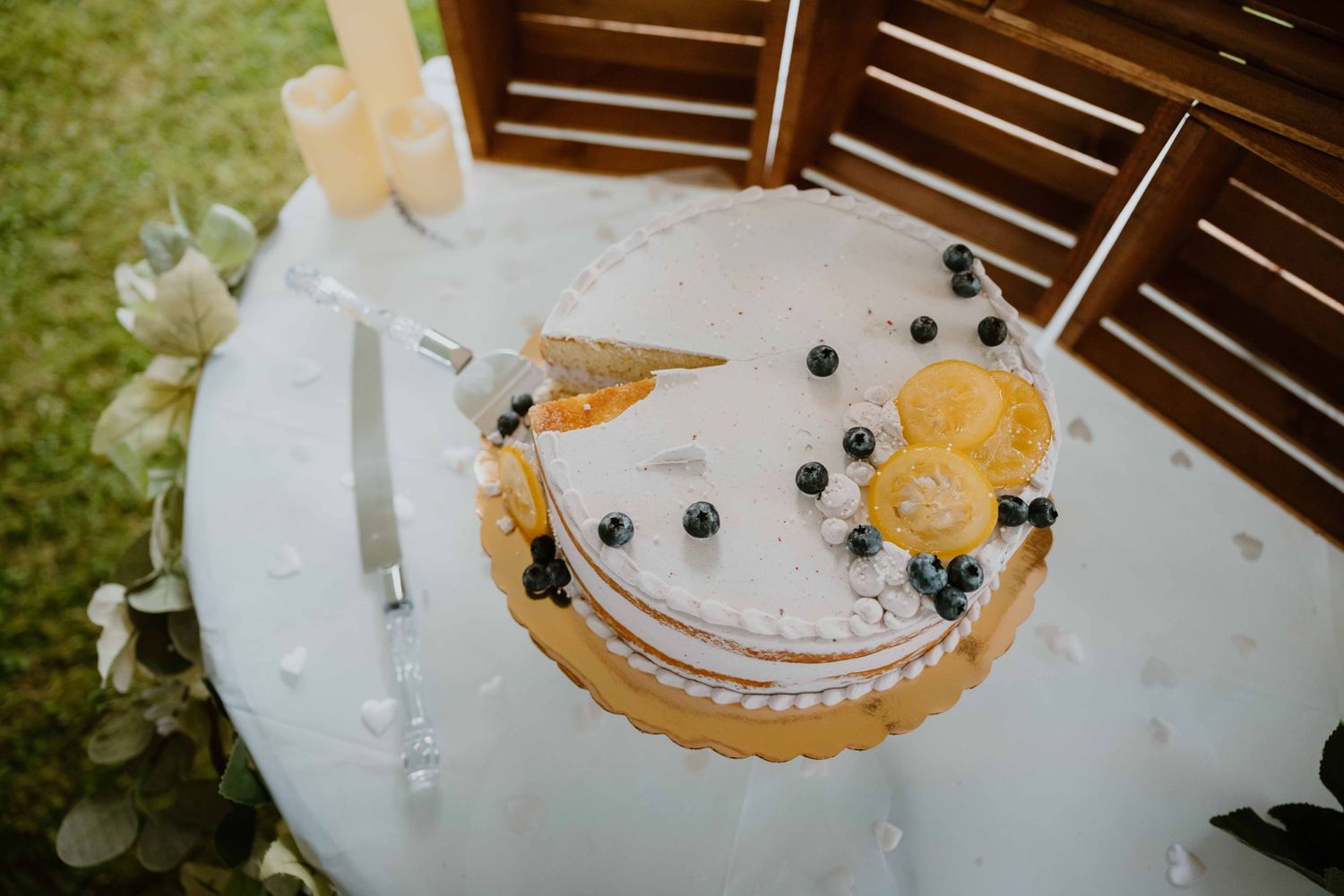 Single-tier white wedding cake topped with blueberries and orange slices on a table.