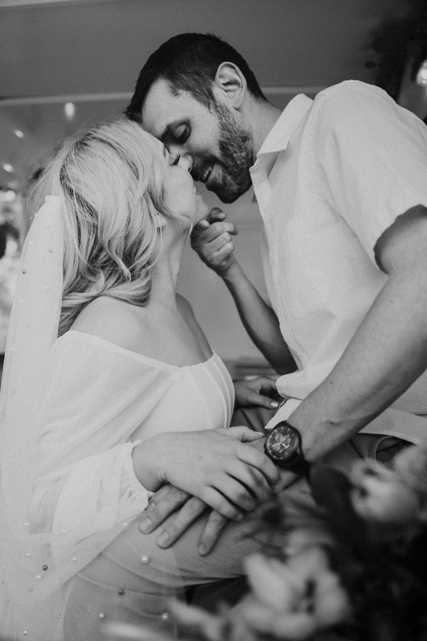 Intimate black and white close-up of bride and groom sharing a kiss at their wedding celebration.